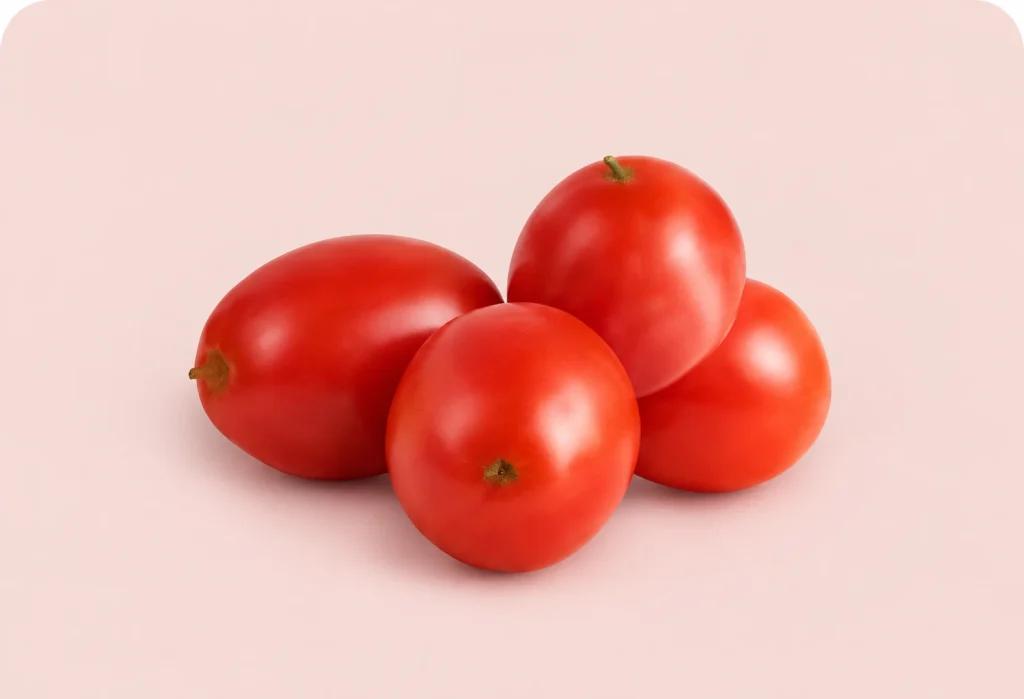 Cuatro tomates rojos maduros sobre fondo rosa claro